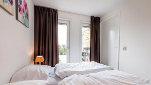 Ein Hotelzimmer mit zwei Betten, einer Lampe und Blick ins Freie.