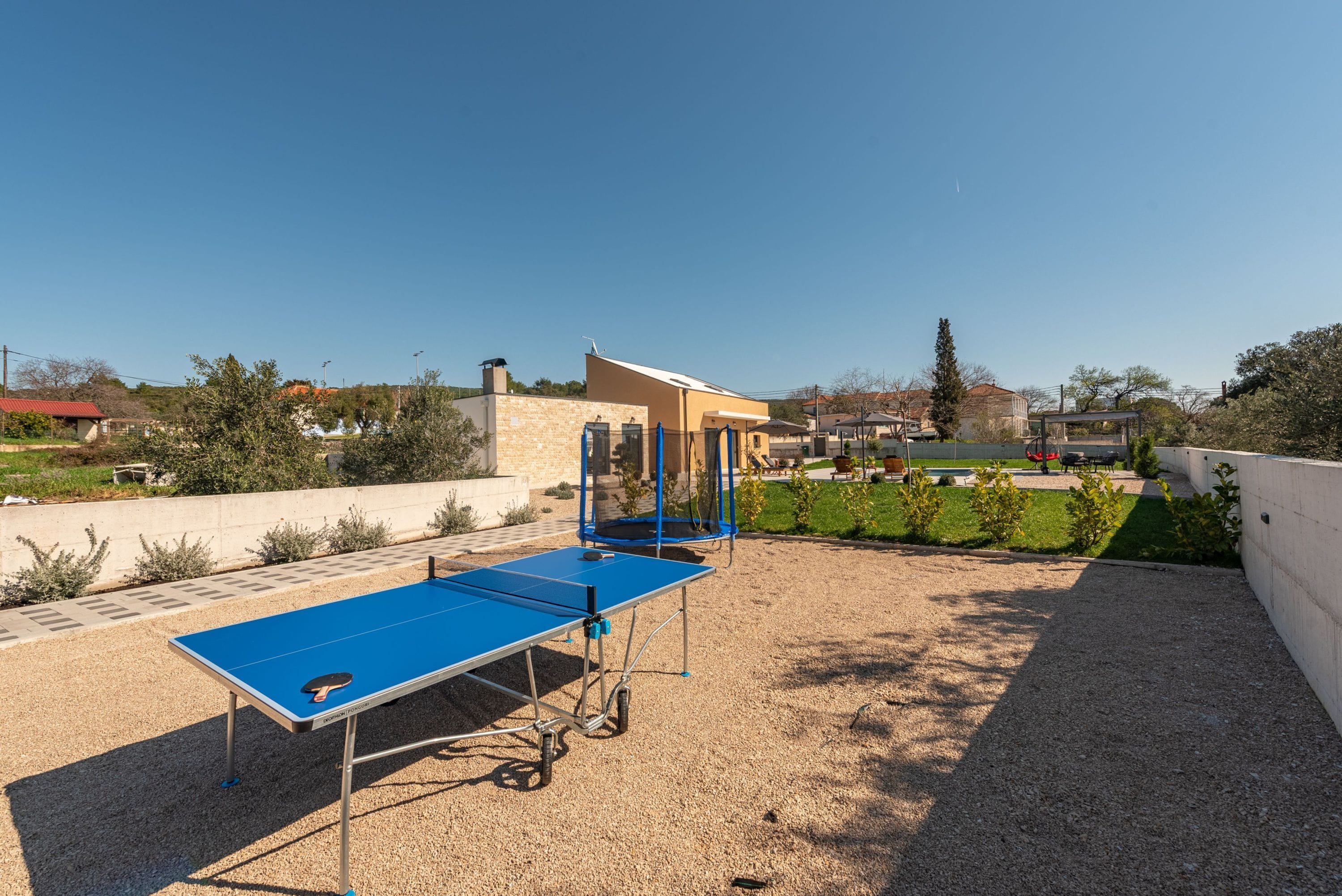 A ping pong table set up outdoors with a clear view of a residential area in the background.