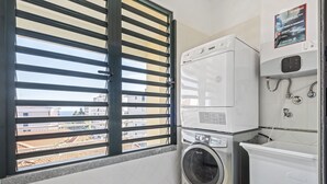 Ένας χώρος πλυντηρίου με πλυντήριο ρούχων, στεγνωτήριο και συνδυαστική συσκευή πλυντηρίου-στεγνωτηρίου.