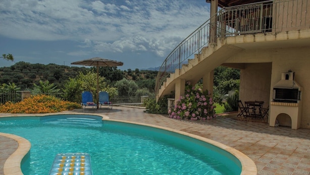 Una piscina con area relax, posti a sedere all'aperto e barbecue.