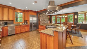 Una cocina amplia con gabinetes de madera, refrigerador de acero inoxidable, encimeras de granito y una isla grande.