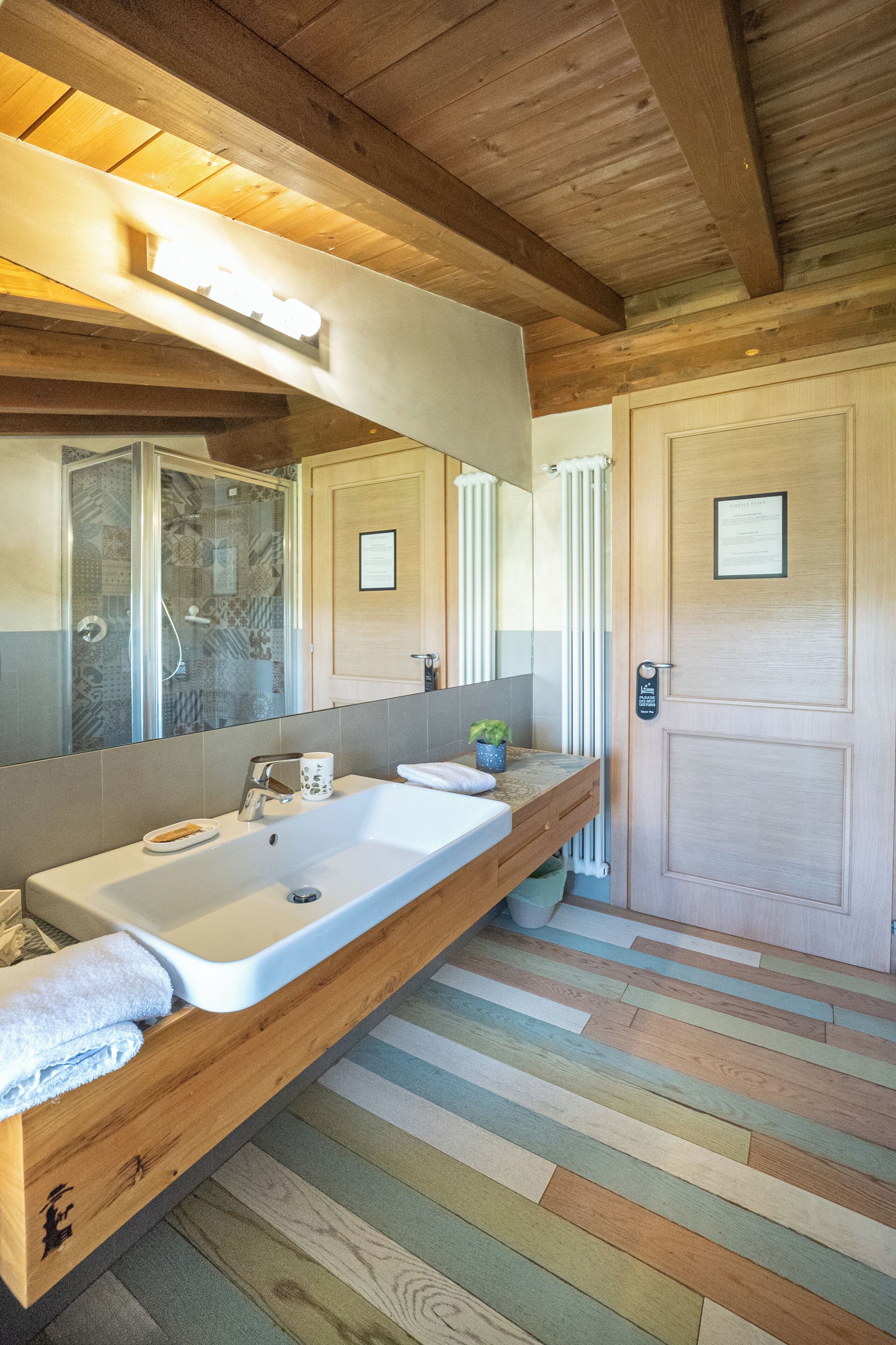 Une salle de bain avec un grand lavabo, un miroir, une douche et un plancher en bois.