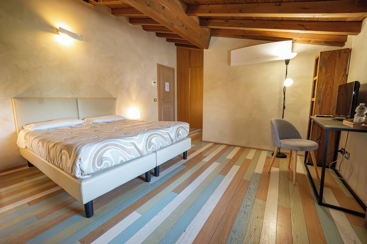 Un dormitorio con cama, escritorio, silla y lámpara.