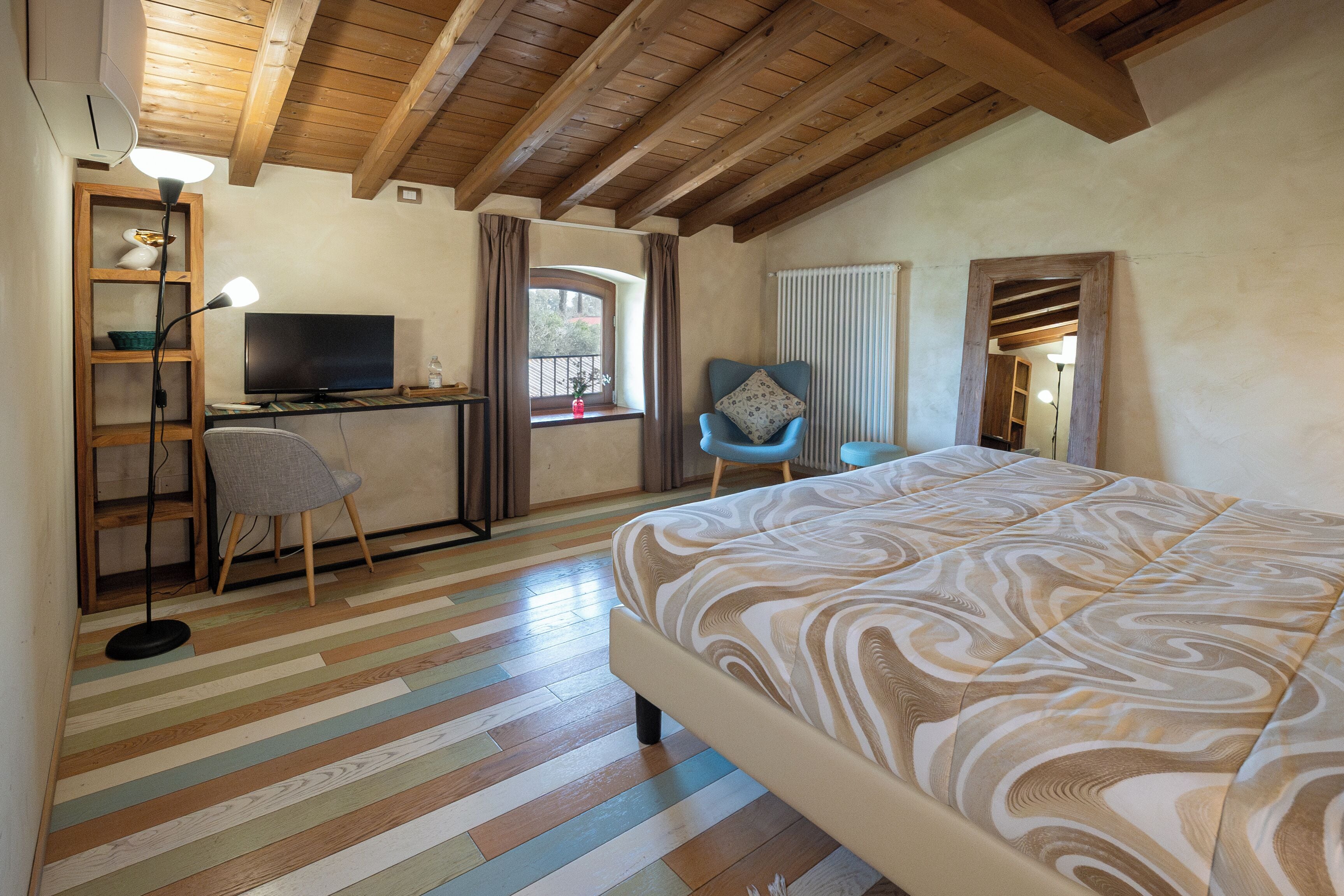 A bedroom with a bed, a desk with a computer, a chair, and a television.