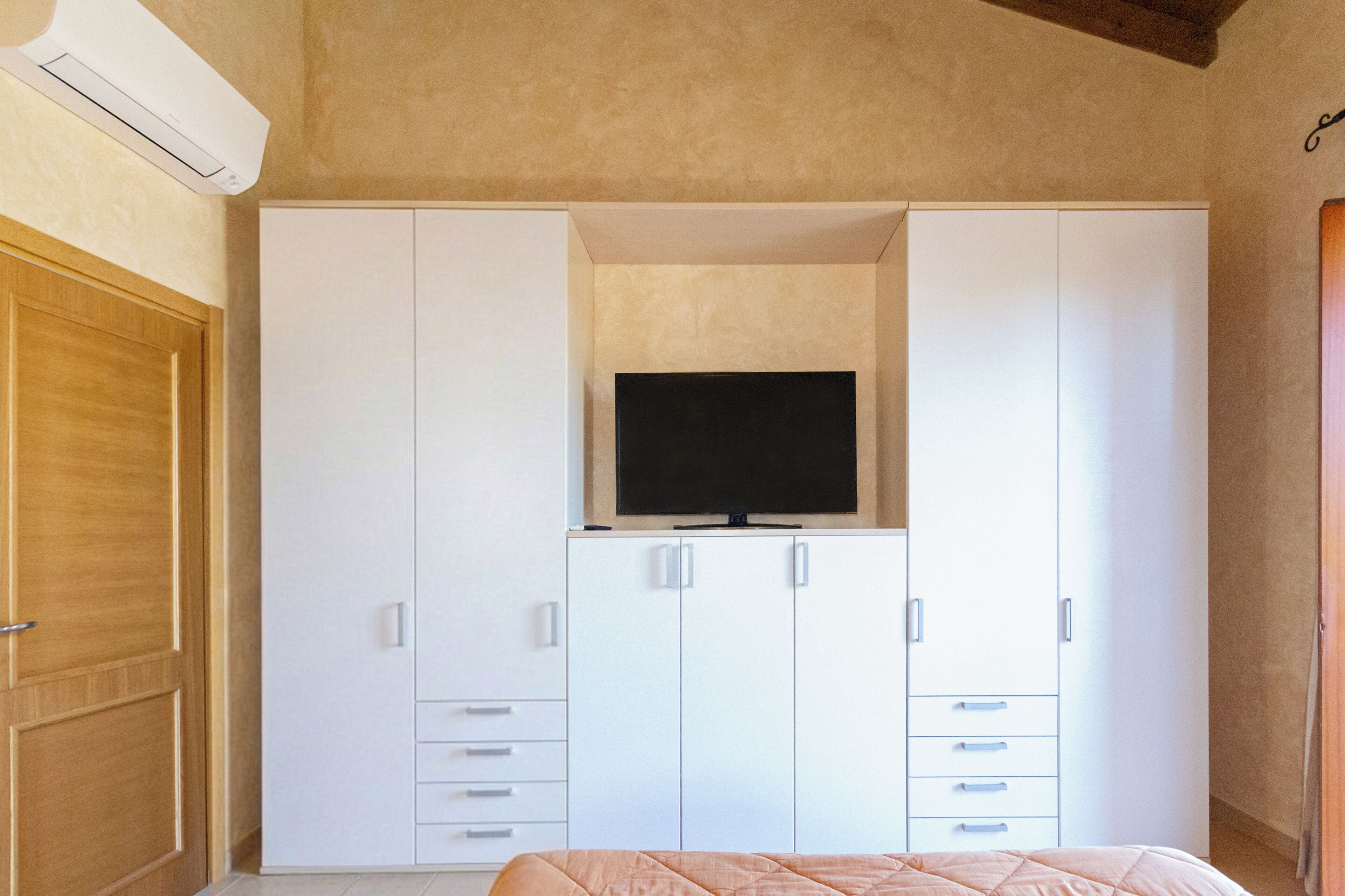 Un dormitorio con cama, televisor y armario.