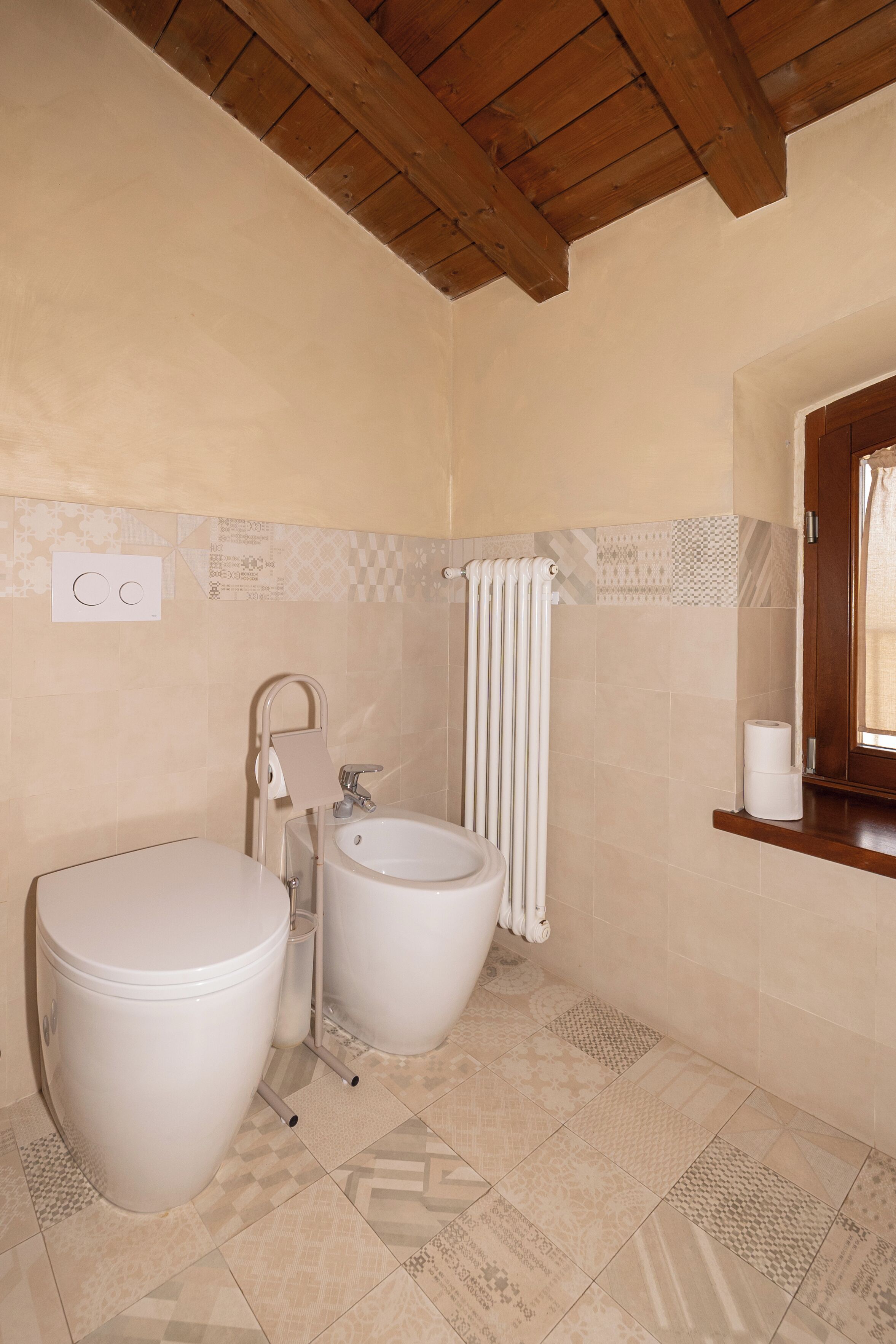 Un baño con inodoro, bidé y un perchero para toallas.