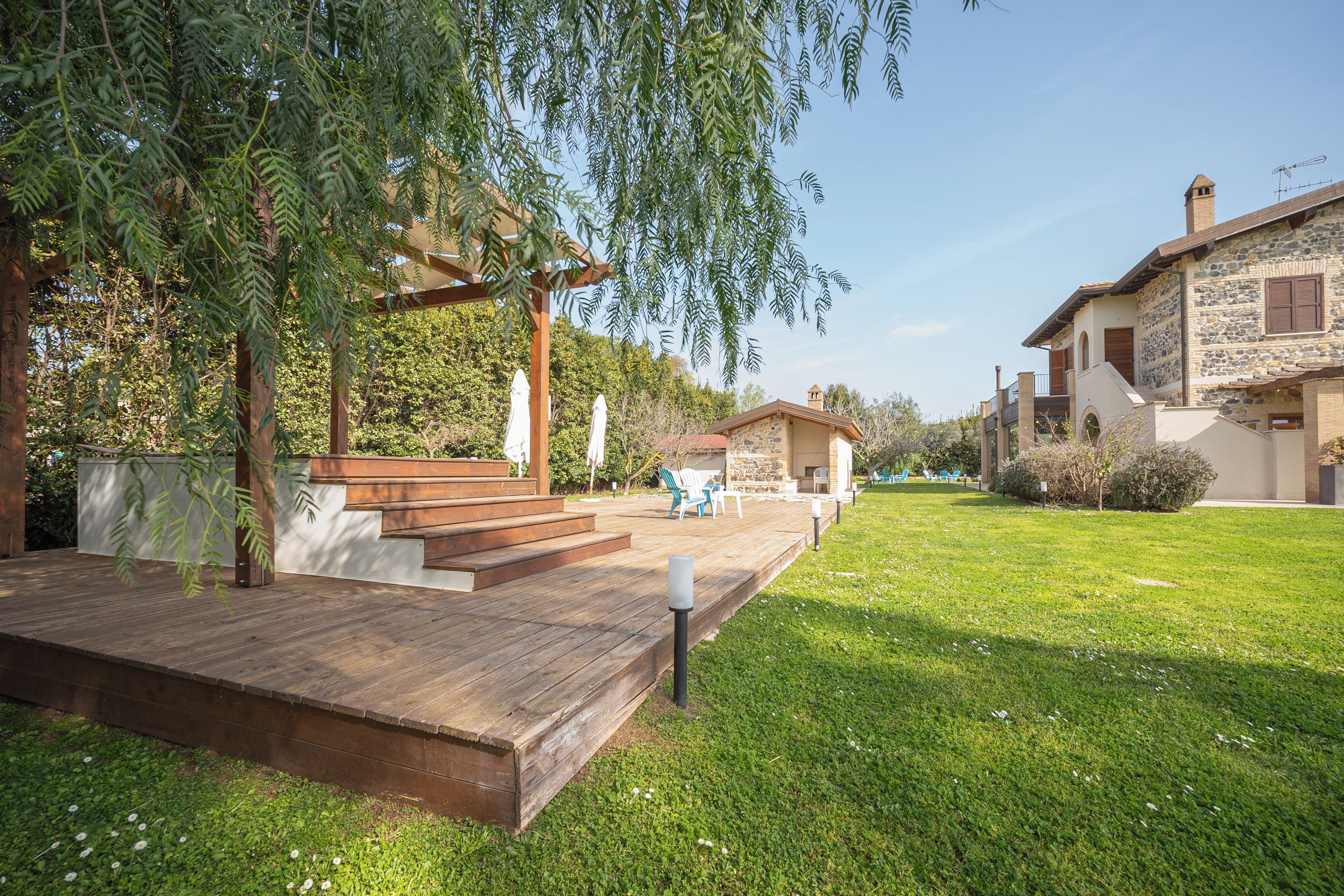 A wooden deck with outdoor furniture, a stone building with a stone facade, and a clear sky.
