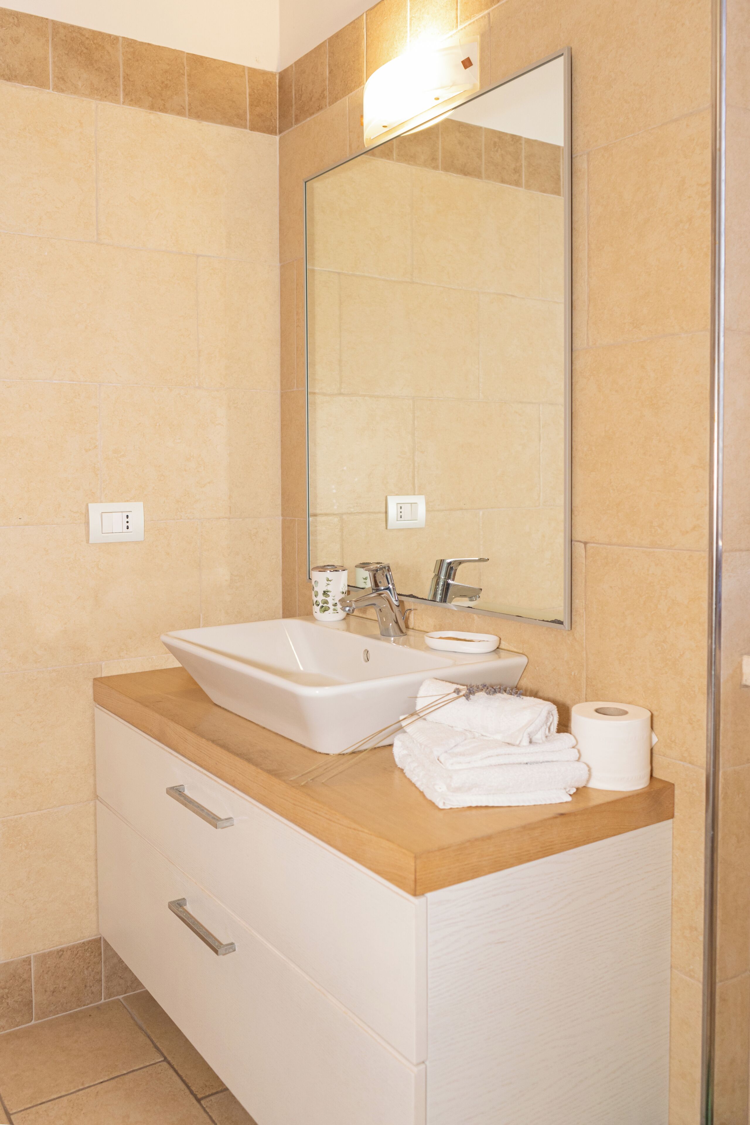Un baño con lavamanos, espejo y toallero.