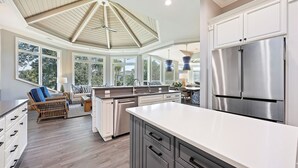 A spacious kitchen with a large island, stainless steel appliances, and a view of the outdoors through large windows. - 3 Brigantine - Incredible 2nd Row Home in Palmetto Dunes (Hilton Head Island)