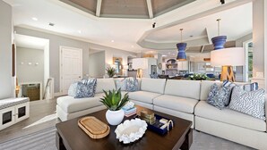 A spacious living room with a large sectional sofa, a coffee table with decorative items, and a kitchen in the background. - 3 Brigantine - Incredible 2nd Row Home in Palmetto Dunes (Hilton Head Island)