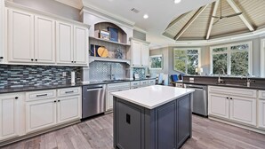 A spacious kitchen with white cabinetry, a central island, and a large window providing natural light. - 3 Brigantine - Incredible 2nd Row Home in Palmetto Dunes (Hilton Head Island)