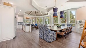 A spacious kitchen with a central island, large windows, and a dining area with a high ceiling and pendant lights. - 3 Brigantine - Incredible 2nd Row Home in Palmetto Dunes (Hilton Head Island)