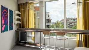 A modern kitchen with a large window, two bar stools, and a refrigerator. - BYPILLOW Flamant (Barcelona)