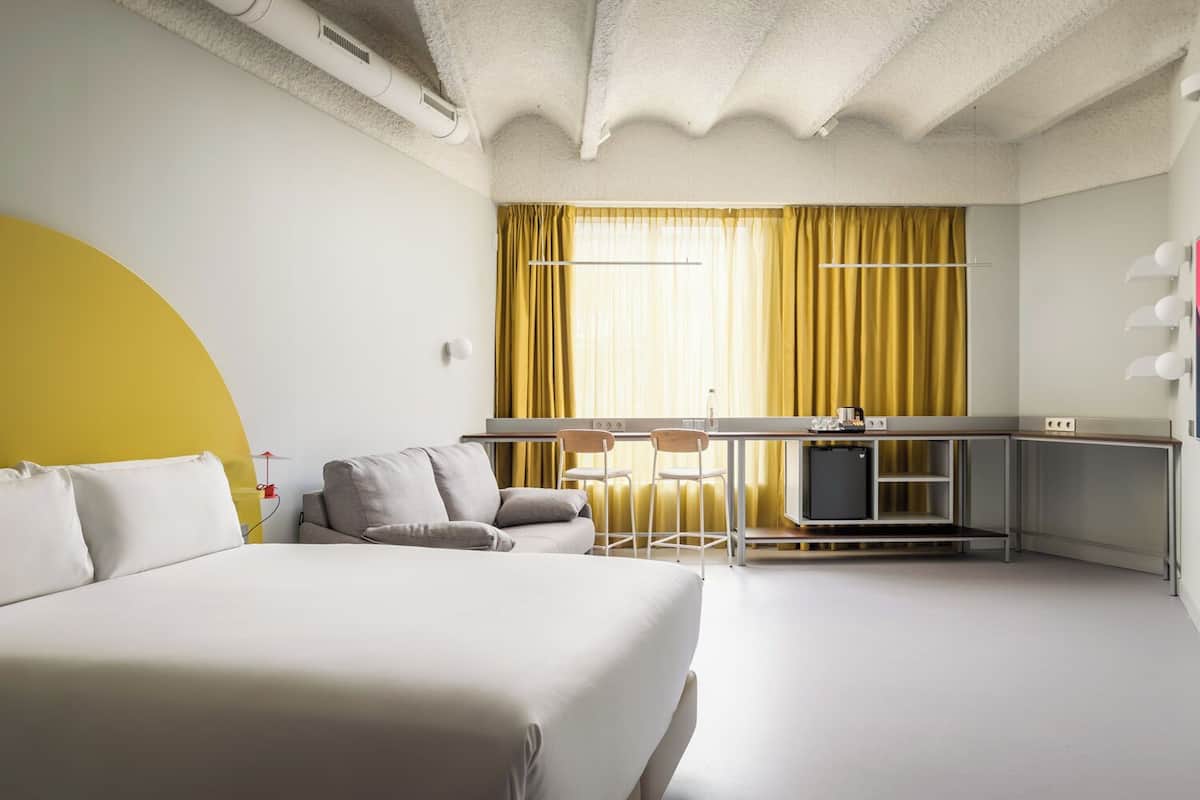 Une chambre d’hôtel moderne avec un grand lit, un petit bureau et un coin repas.