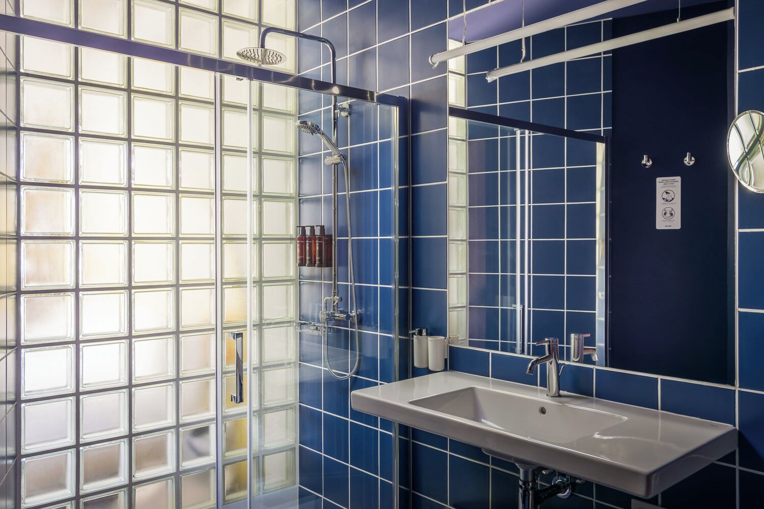 Ein Badezimmer mit einer großen Glasduschtür, einer Dusche, einem Waschbecken und einem Spiegel.