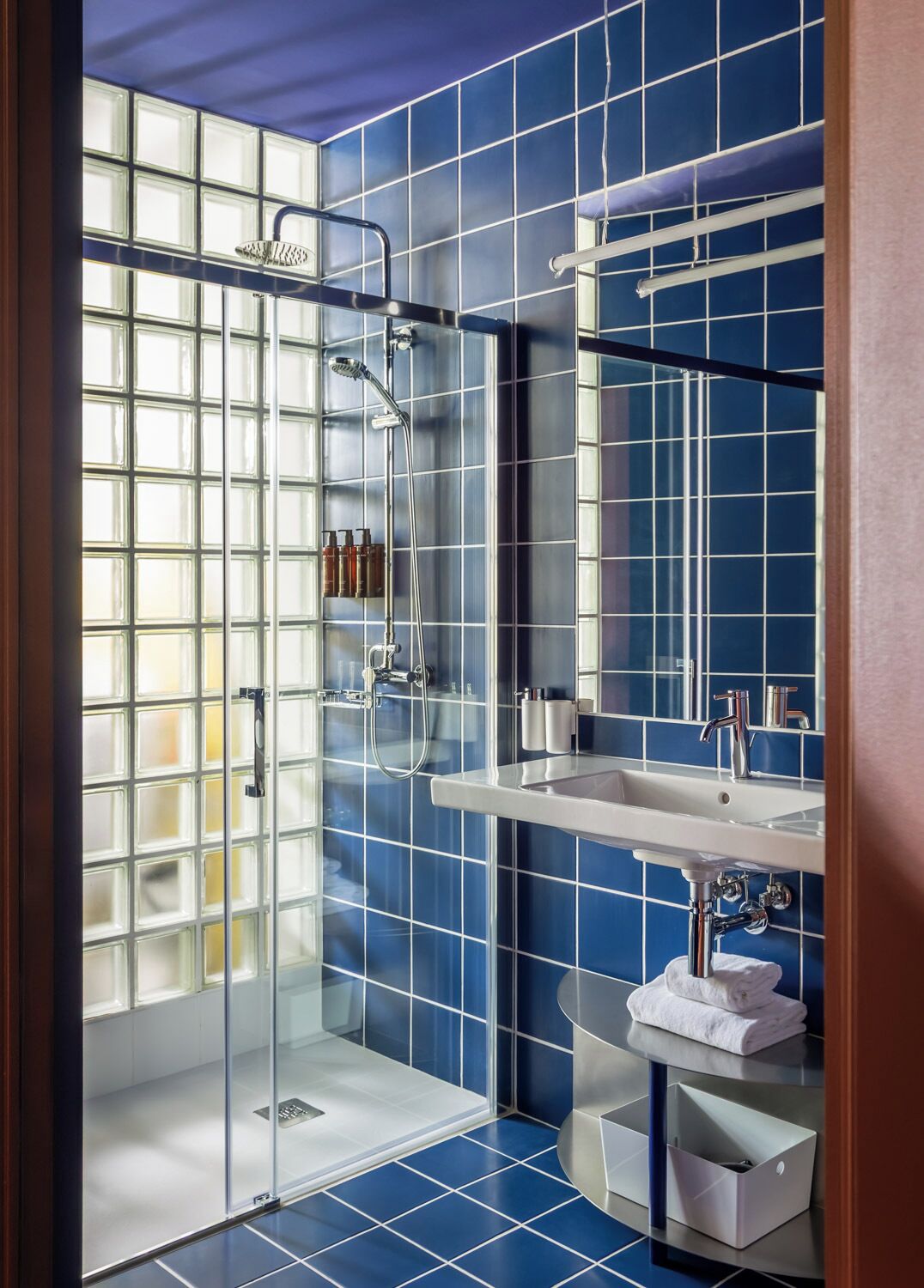 A modern bathroom with a glass shower enclosure, a white sink, and a mirror.