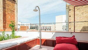 A rooftop terrace with a built-in bench, a red cushion, and a showerhead. - BYPILLOW Flamant (Barcelona)