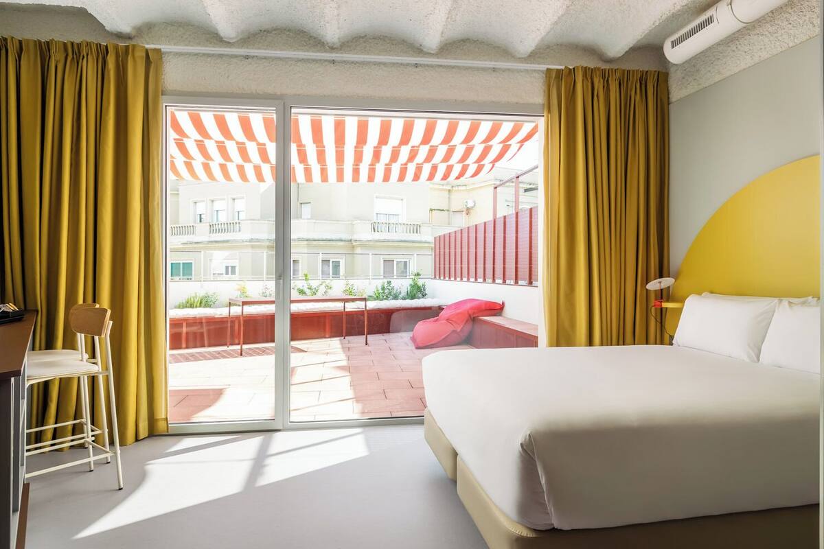 Une chambre d’hôtel avec un lit, une chaise, une table et une vue sur le balcon extérieur.