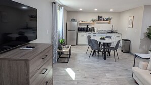 Una cuina moderna amb zona de menjador, televisió de pantalla plana i sofà.