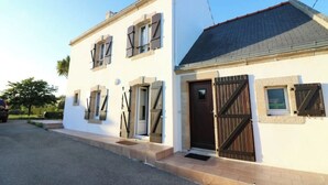 A two-story building with a white facade, a dark brown door, and a tiled roof. - beach 250 meters,large park,wifi, bicycles provided, large terrace for breakfast (Audierne)