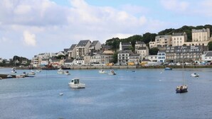 A coastal town with a marina filled with boats, buildings with commercial establishments, and a hilly backdrop. - beach 250 meters,large park,wifi, bicycles provided, large terrace for breakfast (Audierne)