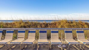 A row of beachside lounge chairs with a view of the ocean and tall grasses in the background. - 2BR Condo in Edgewater Resort w/ Golf, Tennis, Pools & Free Tram Service! (Panama City Beach)