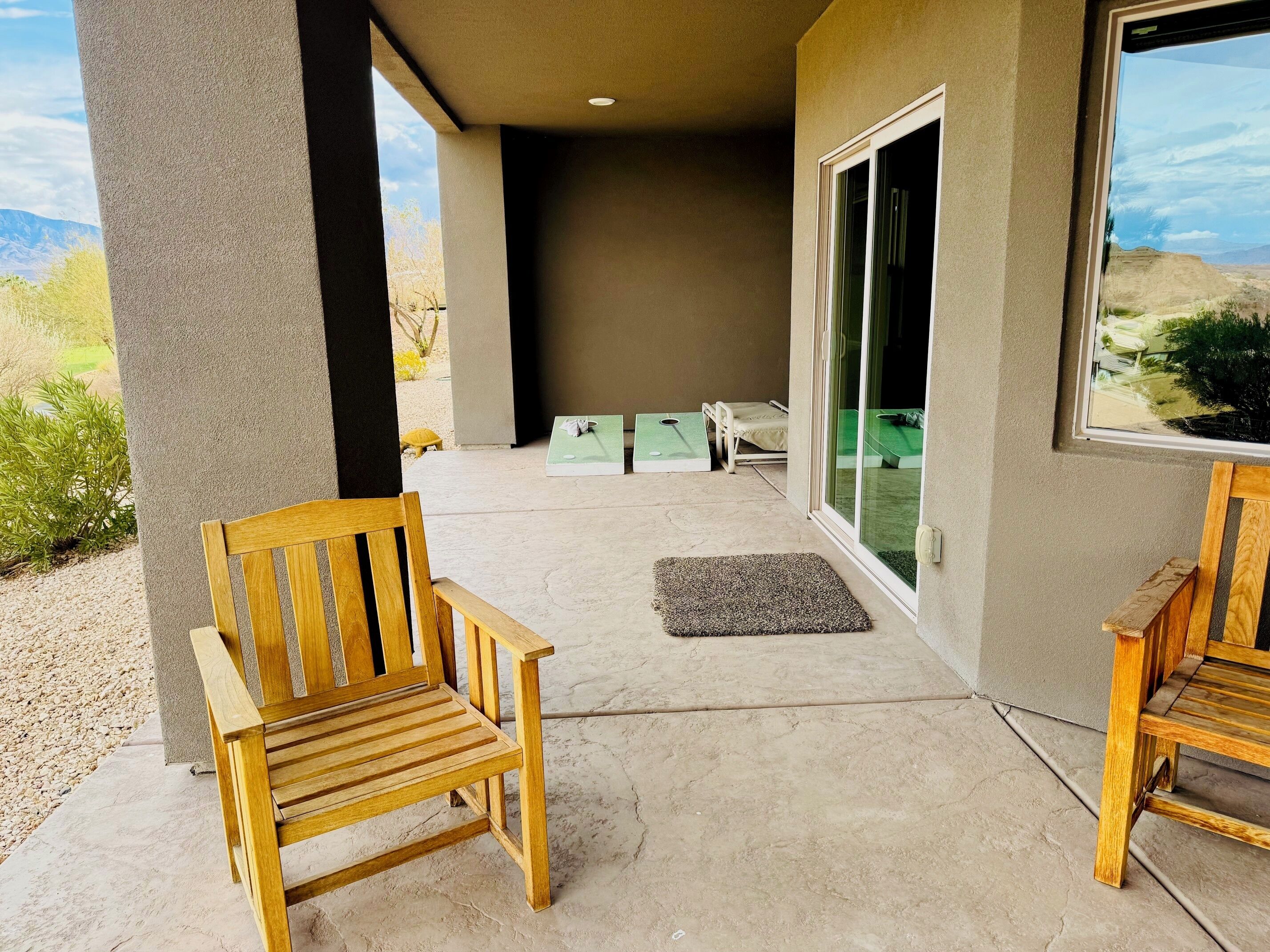 Un espace extérieur aménagé avec deux chaises en bois, une petite table et un banc.