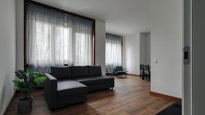 A modern living room with a sectional sofa, a dining area with chairs, and a potted plant. - JOIVY Welcoming 3BR Flat in Milan Centre (Milan)
