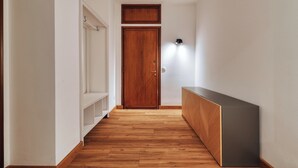 A hallway with wooden flooring, a white wardrobe, and a dark cabinet. - JOIVY Welcoming 3BR Flat in Milan Centre (Milan)