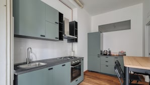 A modern kitchen with grey cabinets, a stainless steel sink, and a wooden dining table. - JOIVY Welcoming 3BR Flat in Milan Centre (Milan)
