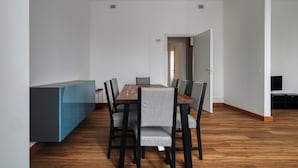 A modern dining area with a wooden table and grey upholstered chairs, a blue console table, and a wooden floor. - JOIVY Welcoming 3BR Flat in Milan Centre (Milan)