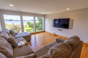 Una sala de estar con un ventanal grande, un televisor de pantalla plana montado en la pared y un sofá modular.