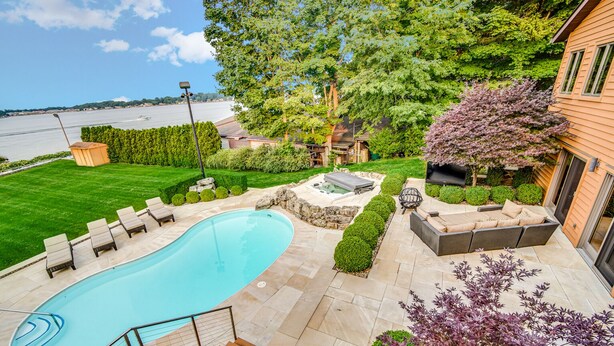Un jardin avec une piscine, un espace salon extérieur et une vue sur l’eau.