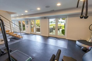 A gym with a treadmill, exercise balls, and a staircase. - Lakefront Tech-savvy Home with Seasonal Pool & Hot Tub (La Porte)