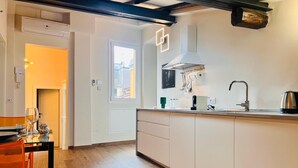 Moderni keittiö, jossa on keskeinen saareke, integroidut kaapit ja ikkuna, josta tulee luonnonvaloa.