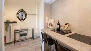 A compact kitchen with a countertop, a coffee machine, a wine glass, and a basket of snacks. - Acropolis Vista Retreat (Athina)