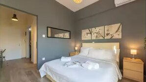 A modern hotel room with a large bed, bedside lamps, and artwork on the wall. - Acropolis Vista Retreat (Athina)