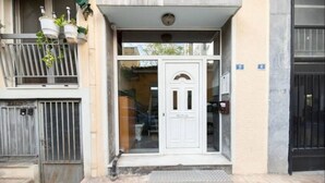 A building entrance with a white door, a small porch, and a metal gate. - Acropolis Vista Retreat (Athina)