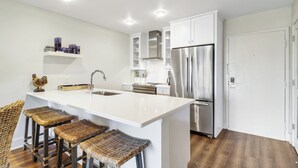 A modern kitchen with white cabinetry, stainless steel appliances, and a central island with bar stools. - Sunset Rentals- 682 Mariners Way (Hilton Head Island)