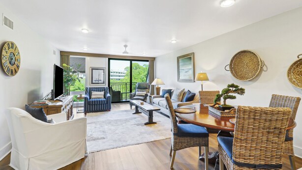 A spacious living area with a sofa, chairs, a dining table, and a large window offering a view of greenery. - Sunset Rentals- 682 Mariners Way (Hilton Head Island)