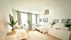 A modern bedroom with two beds, a large rug, and a white dresser. - Arbio Monteurzimmer Rüdersdorf 4 people (Rüdersdorf bei Berlin)