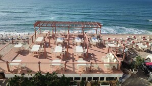 Un restaurante junto a la playa con terraza y vistas al océano.