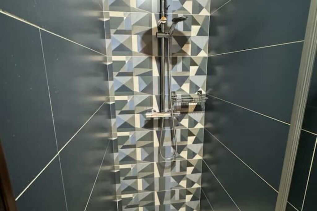 Une douche avec un motif géométrique en carreaux sur le mur.