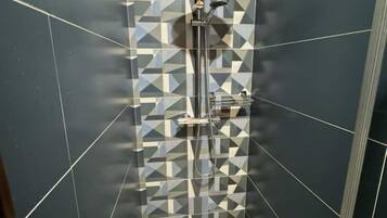 Une douche avec un motif géométrique en carreaux sur le mur.