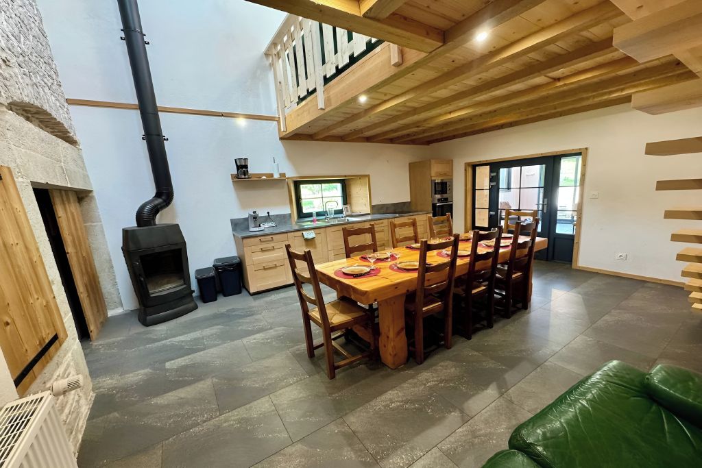 Een ruime keuken met een eethoek, een open haard en een vide.