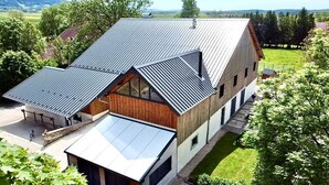 A modern building with a sloped roof, large windows, and a covered entrance. - Cosy cottage with relaxing view and outdoor barbecue (Laviron)