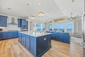 A modern kitchen with a central island, built-in appliances, and a view to the sea.
