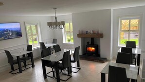 A dining area with a fireplace, a TV mounted on the wall, and large windows. - Rostrevor Valley 5-br, Sleeps 10 w/ Hot Tub & View (Newry)