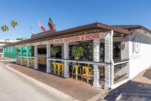 A seaside restaurant with outdoor seating and a sign reading 'PIZZA PASTA SEAFOOD & MORE'. - Flagler Ave 1 Bedroom/1 Bath-Eat, Drink, Play! (New Smyrna Beach)