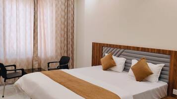 Una habitación de hotel moderna con una cama grande, un ventilador de techo y un escritorio con sillas.
